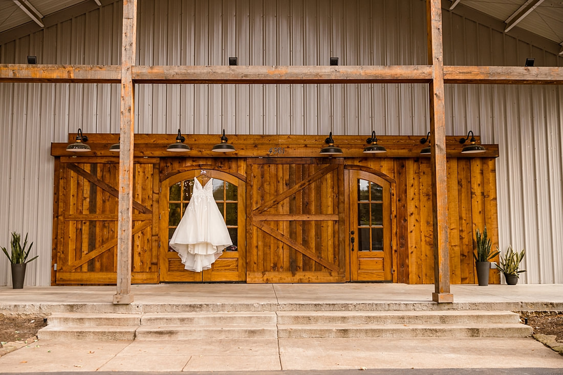 Maggie Louise wedding gown hanging on barn door at Avon Acres in Memphis, TN