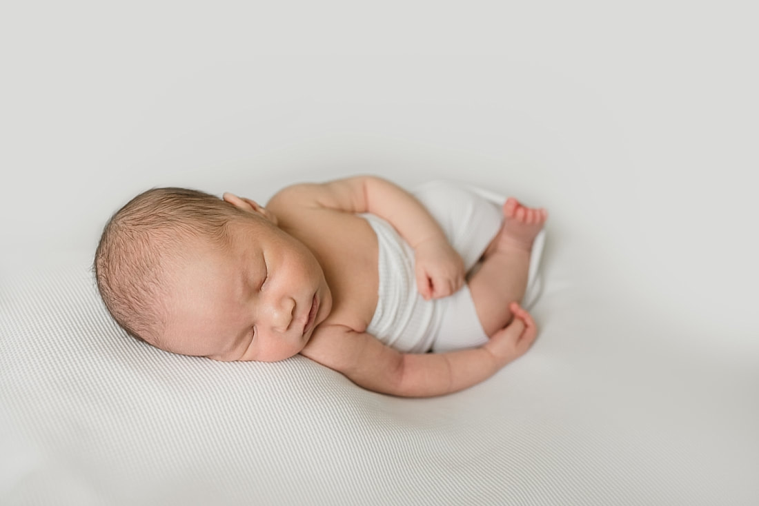 cute newborn baby boy wrapped in white for newborn photo shoot in memphis