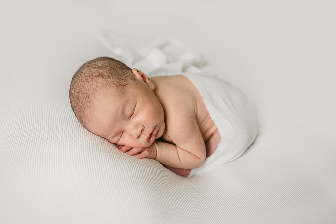 cute newborn baby boy wrapped in white for newborn photo shoot in memphis