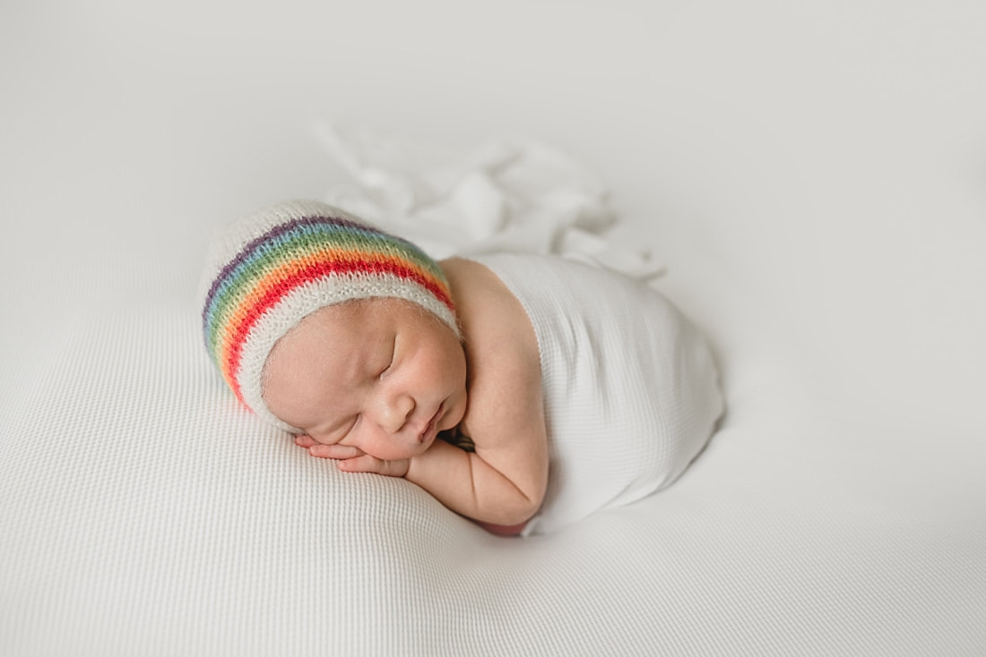 rainbow baby boy wearing rainbow bonnet for newborn photo shoot in memphis