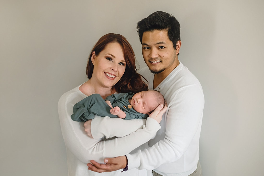 new family of three, mom and dad holding newborn baby boy during newborn photos in memphis, tn