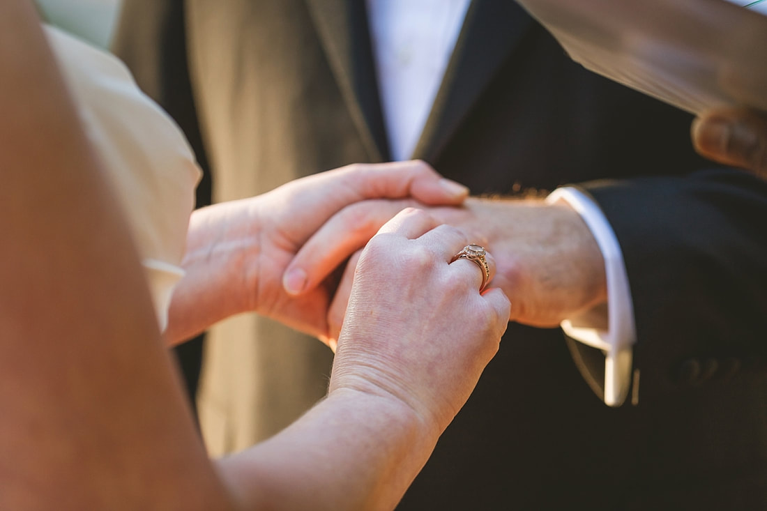 Bride putting the groom's wedding ring on his hand during wedding ceremony at the Collierville Town Square