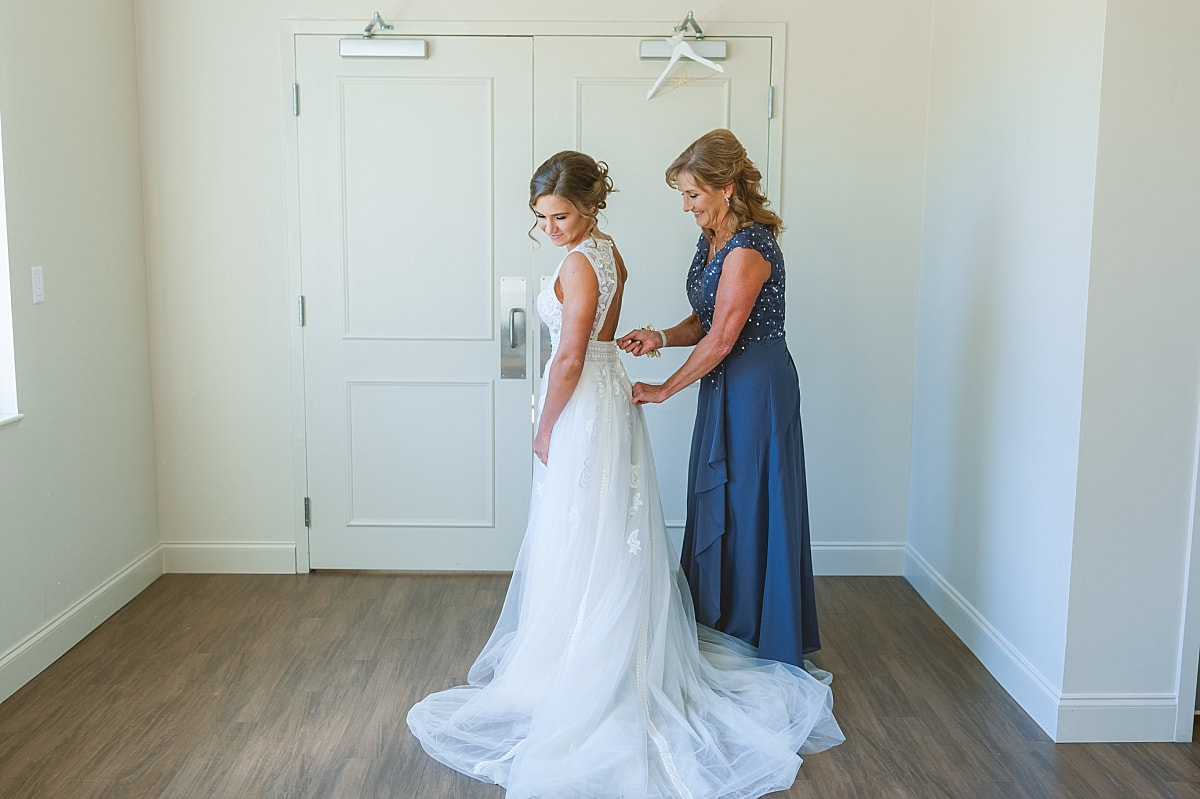 bride's mother zipping up her wedding dress
