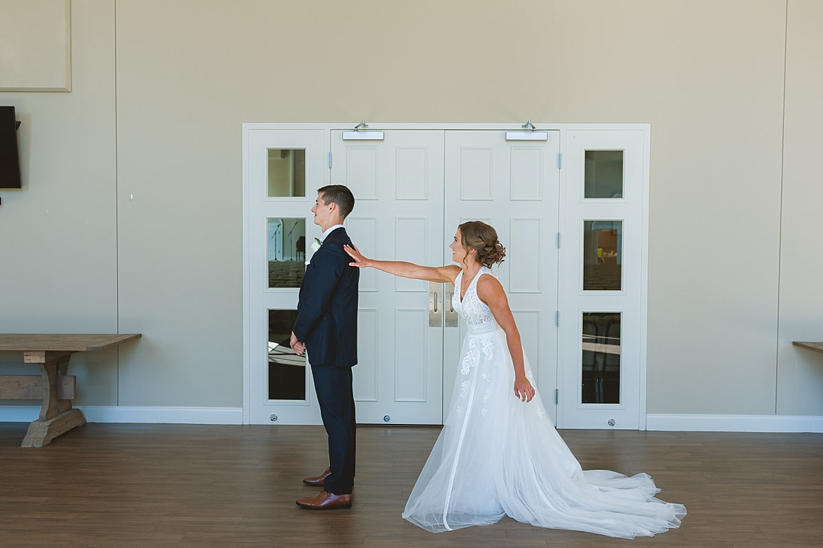 bride tapping her groom on the shoulder for their first look