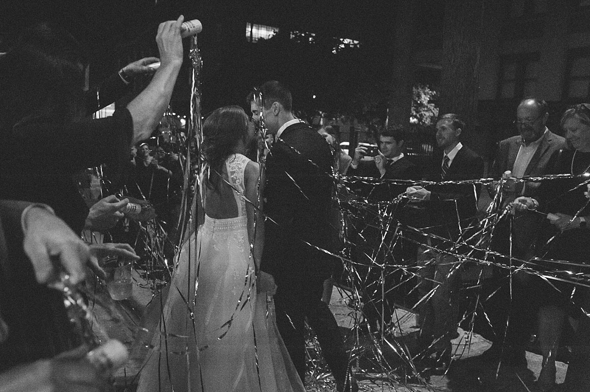 bride and groom exiting their wedding reception as wedding guests shoot confetti at them at the robinson gallery downtown memphis