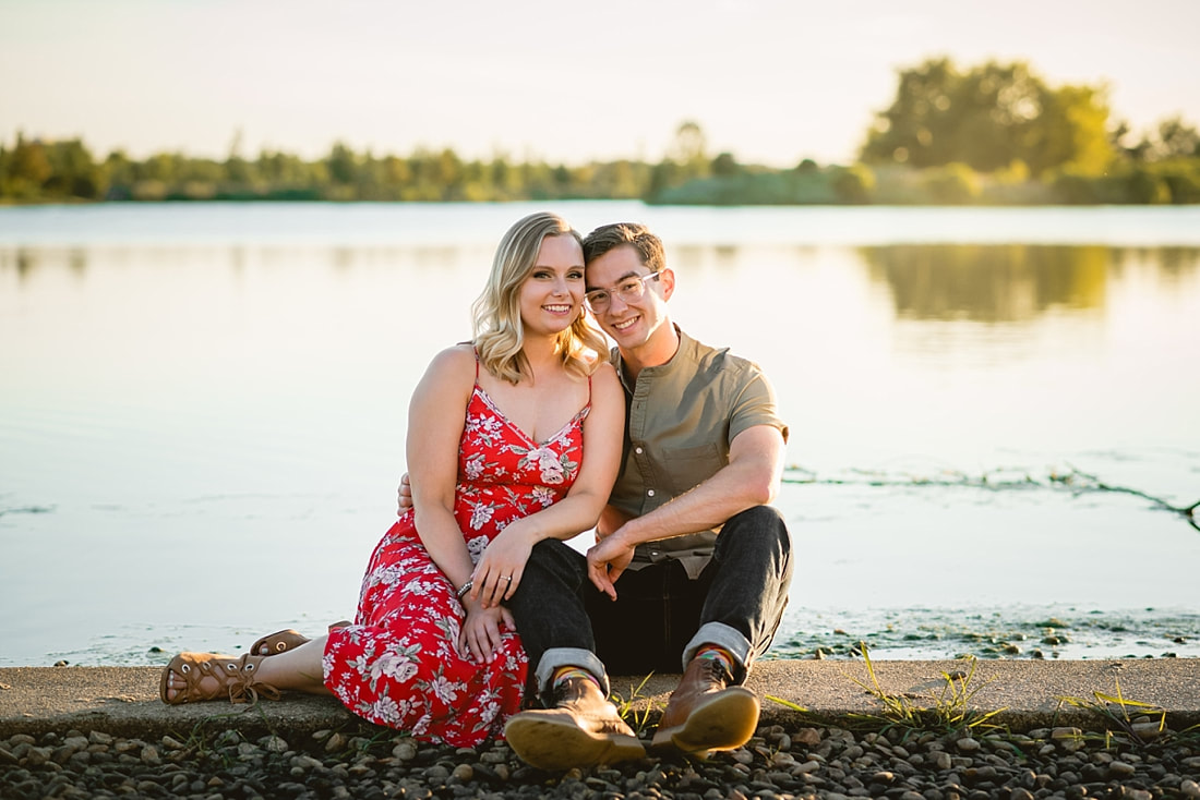 couple posing for engagement photos by the lake at shelby farms park in memphis, tn