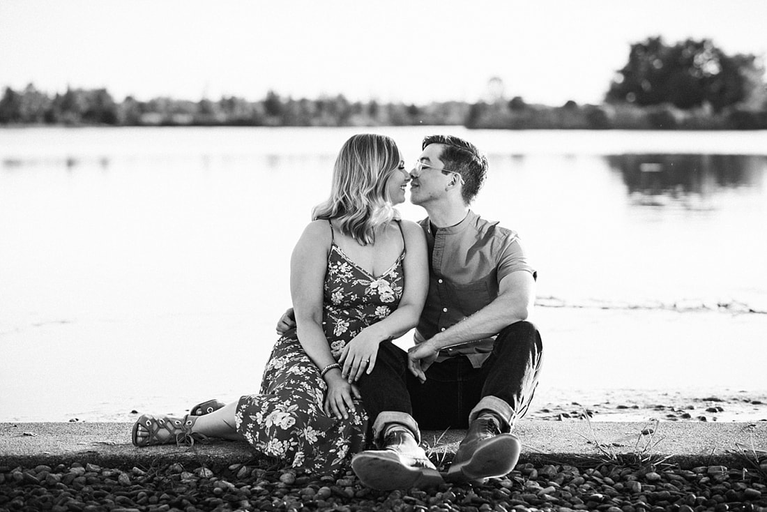 couple posing for engagement photos by the lake at shelby farms park in memphis, tn