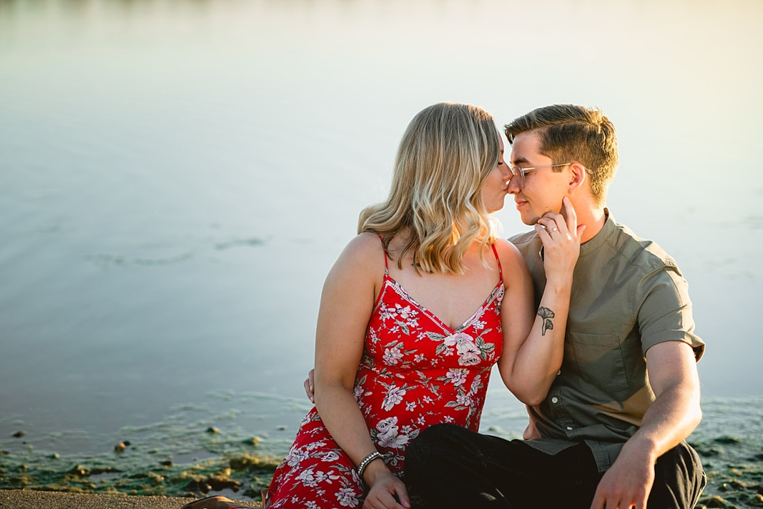 couple posing for engagement photos by the lake at shelby farms park in memphis, tn