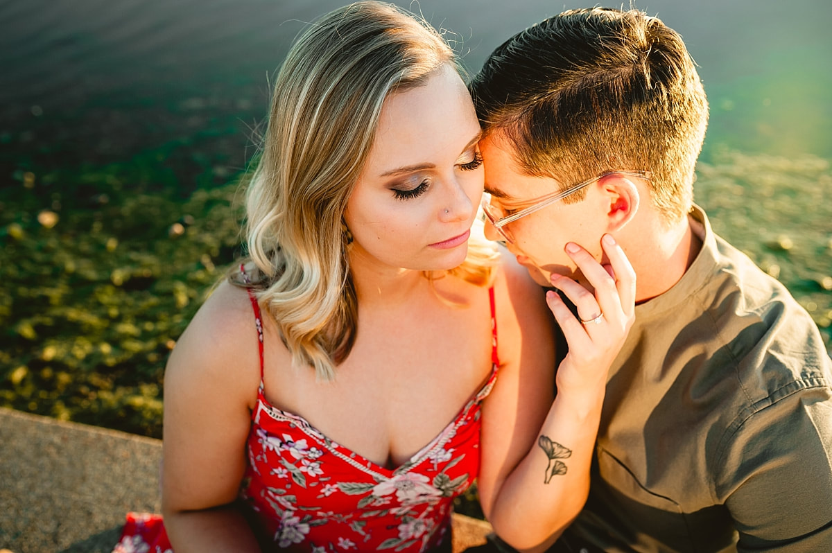 couple posing for engagement photos by the lake at shelby farms in memphis, tn