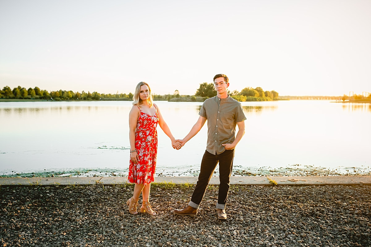 couple posing for engagement photos by the lake at shelby farms park in memphis, tn