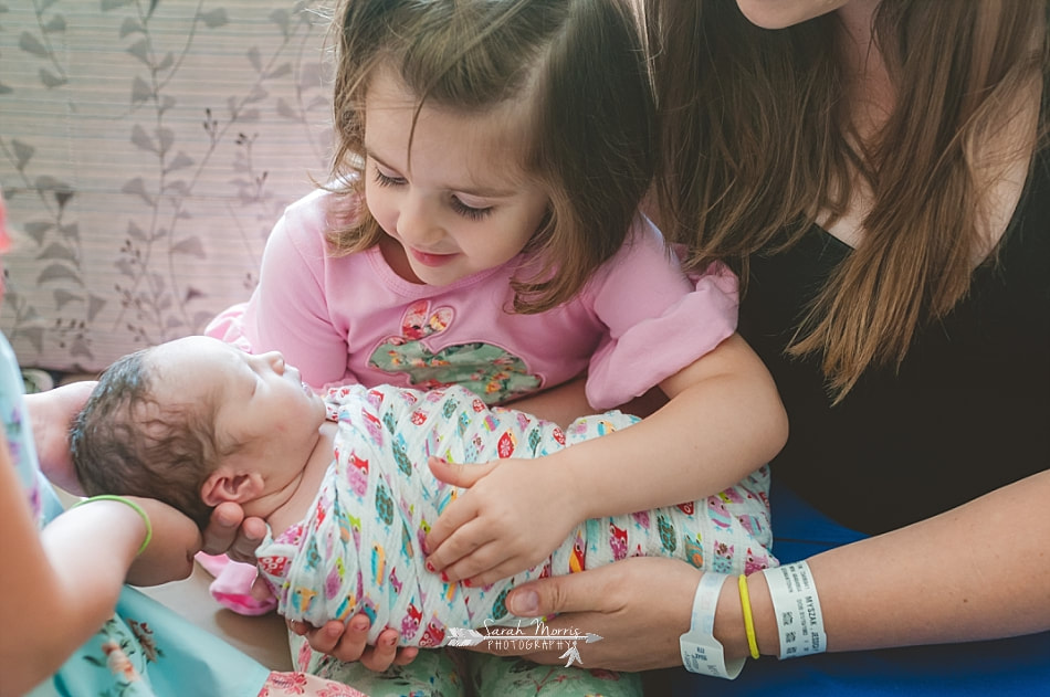 Mother helping her daughter hold her newborn baby sister at Methodist Le Bonheur Germantown Hospital