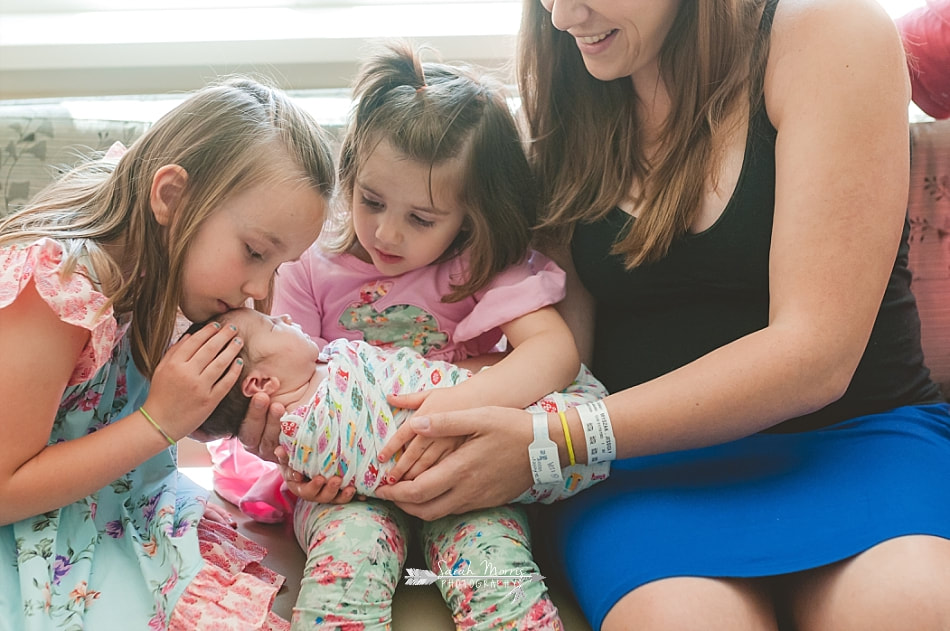Big sisters admiring and kissing their newborn baby sister at Methodist Le Bonheur Germantown Hospital