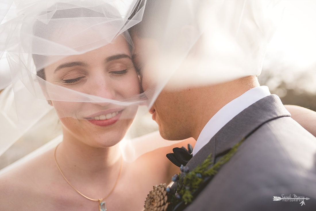 close up of bride and groom snuggling under bride's wedding veil at memphis botanic garden