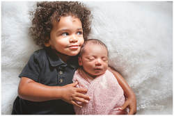newborn photos with toddler sibling on white fur