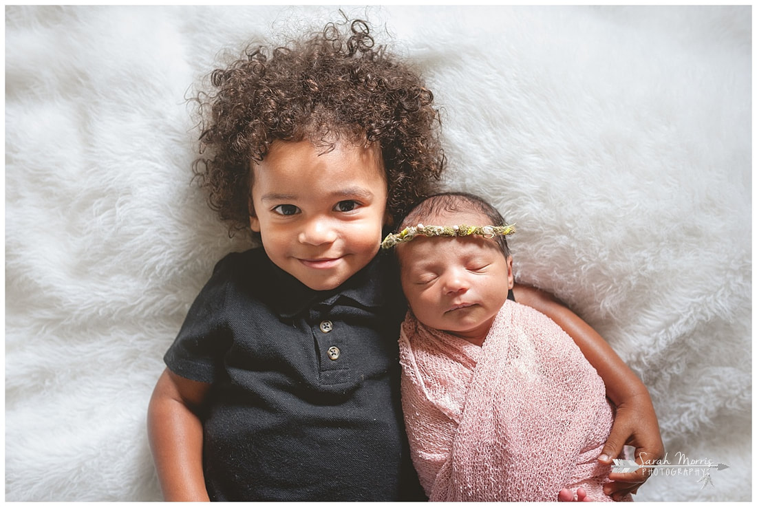 newborn photos with toddler sibling on white fur