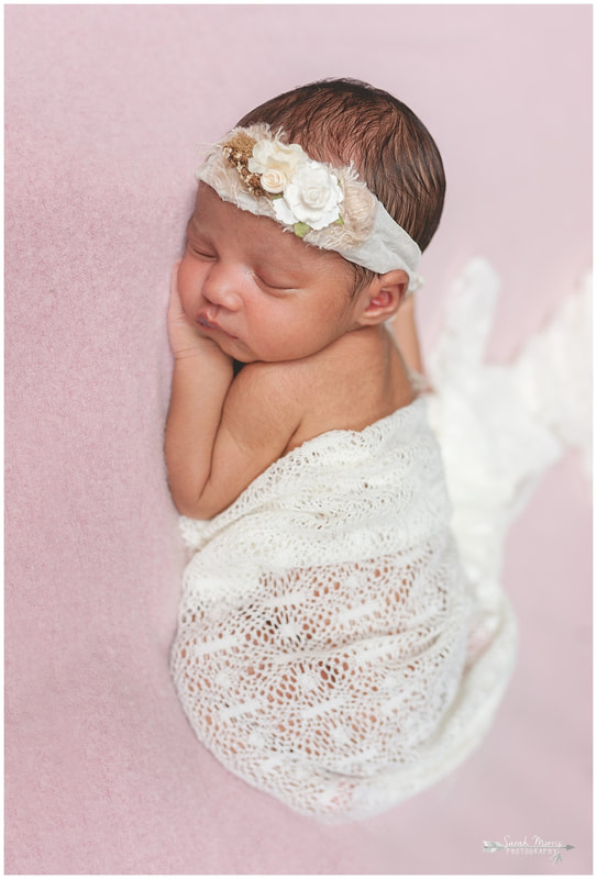 newborn photos of baby girl on pink blanket wearing flower headband