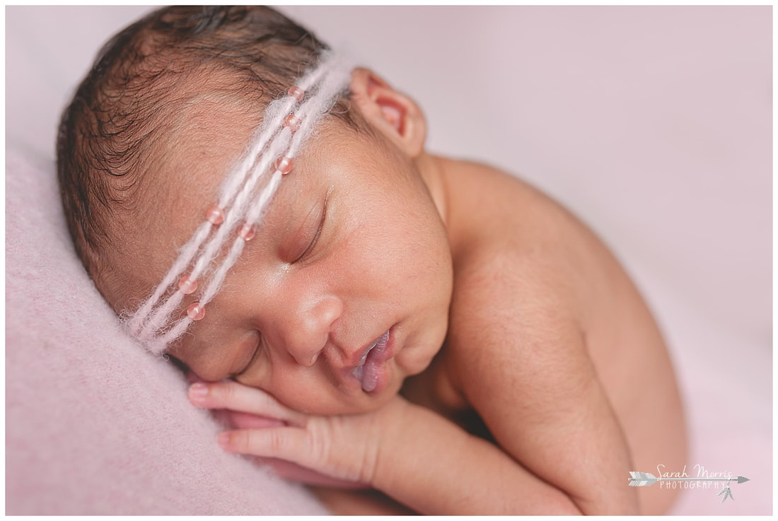 newborn photos of baby girl on pink blanket wearing pink headband
