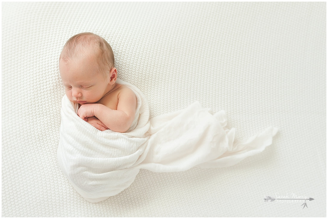 Newborn photo of baby boy sleeping on white blanket