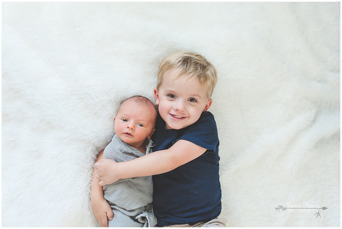 Newborn photos with older siblings on fur rug