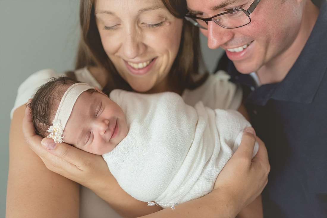 Mother and father looking down at their beautiful newborn baby girl while she smiles
