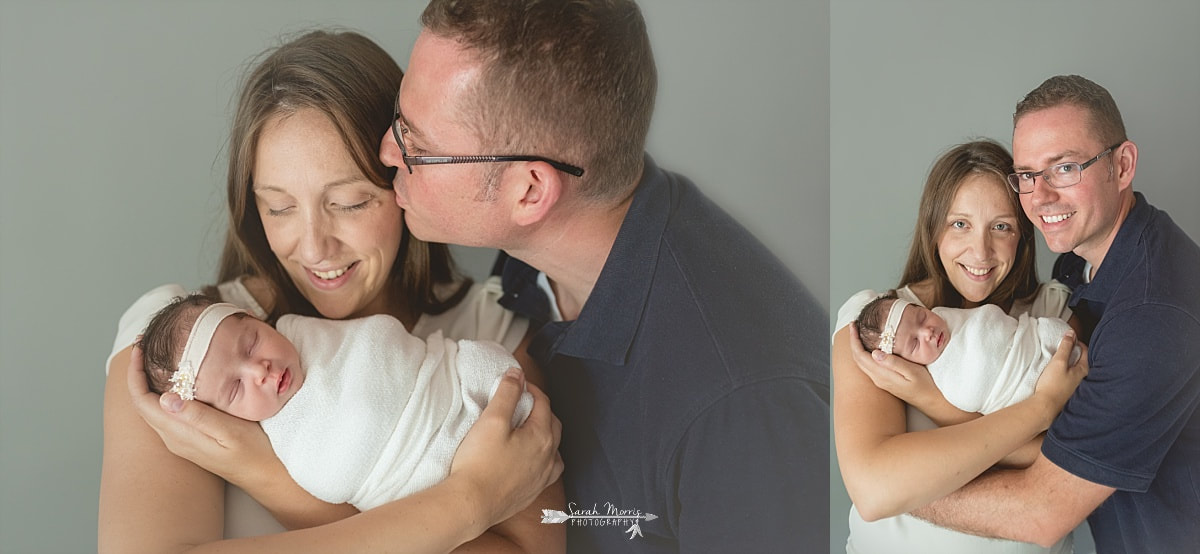 mother holding her newborn baby girl while daddy wraps his arms around them both