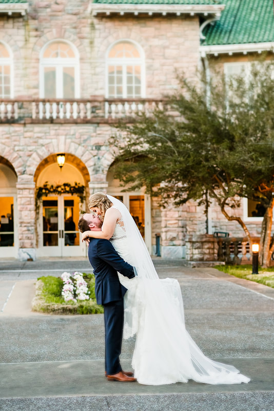 Groom picking bride up to kiss her in front of the Pink Palace, Wedding Photographer in Memphis, TN