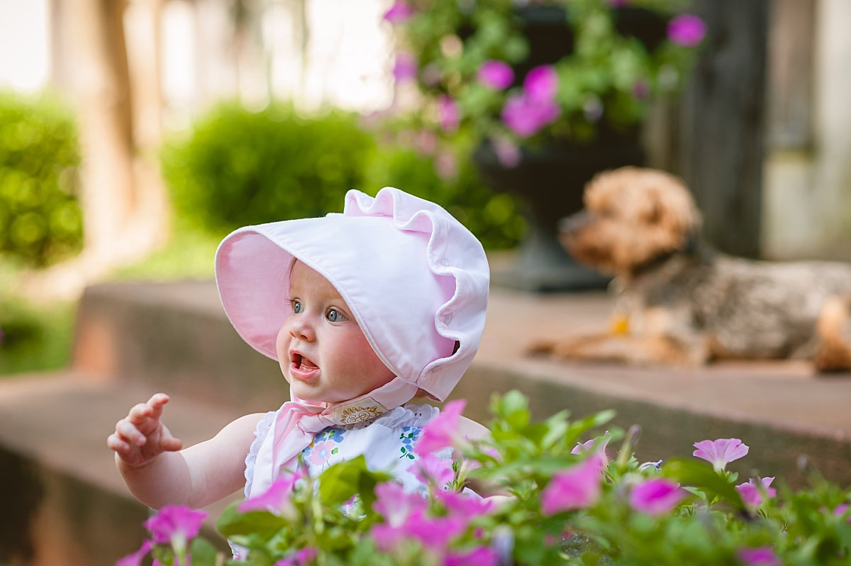 baby girl's first birthday portrait, wearing a monogrammed bubble and Beaufort bonnet on the front porch during in home lifestyle family session in collierville, tn