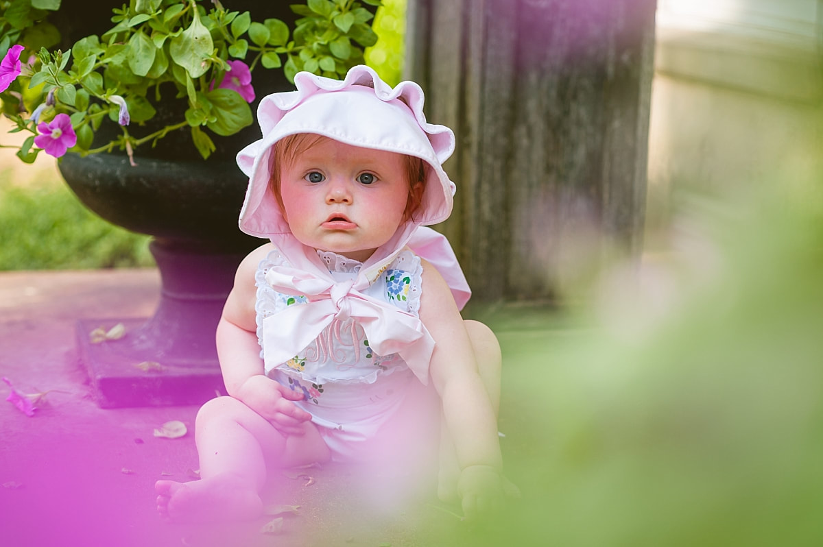 baby girl's first birthday portrait, wearing a monogrammed bubble and Beaufort bonnet on the front porch during in home lifestyle family session in collierville, tn