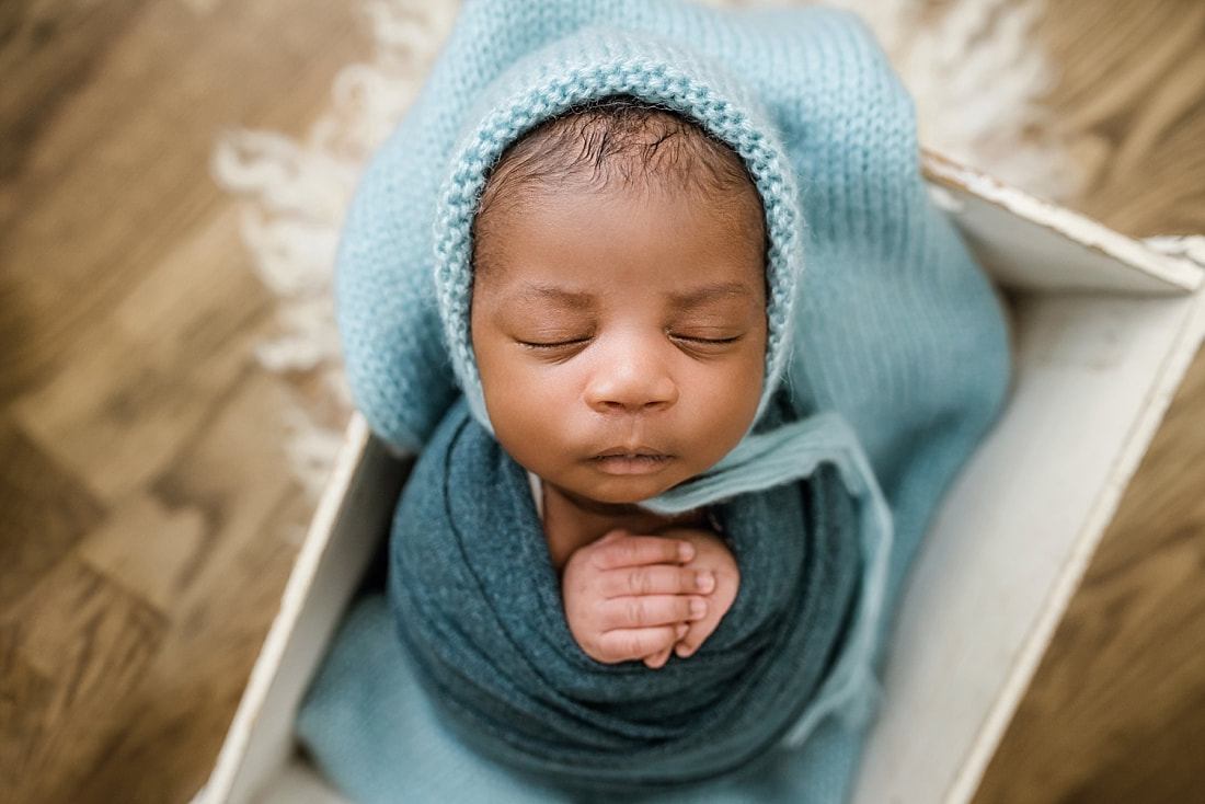 newborn baby wrapped in blue in wooden box for newborn session in Memphis, TN