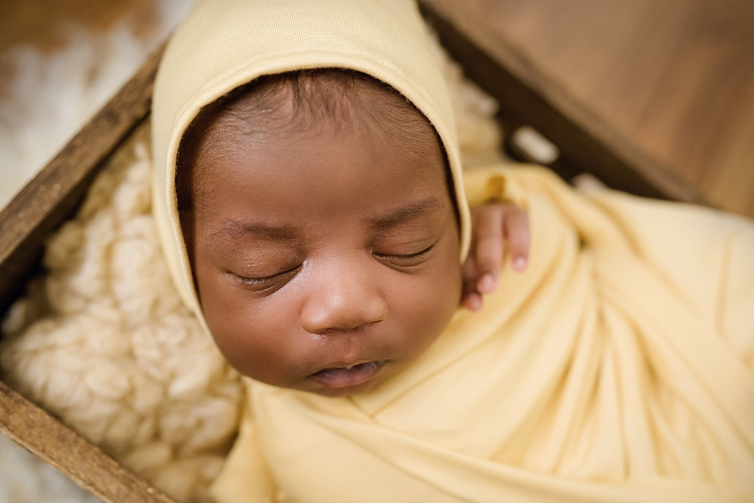 baby wrapped in yellow and sleeping in wooden box for newborn photos in Collierville, TN