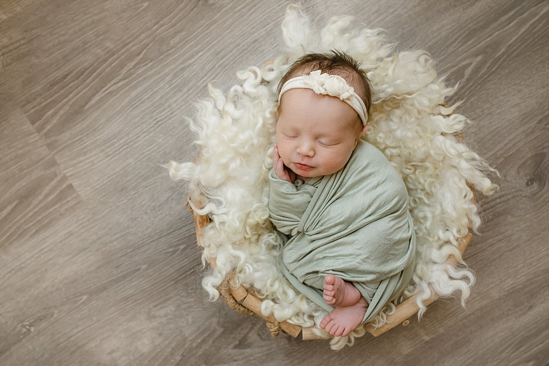 baby girl wrapped in green, sleeping in basket for newborn photos in Memphis, TN