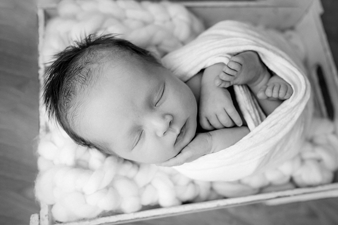 baby girl swaddled in white blanket, sleeping in basket for newborn photos in Memphis, TN