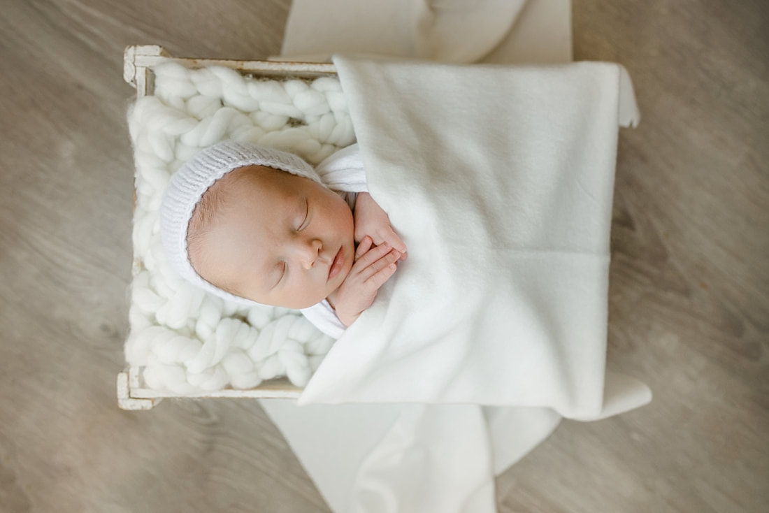 baby girl swaddled in white blanket, sleeping in basket for newborn photos in Memphis, TN