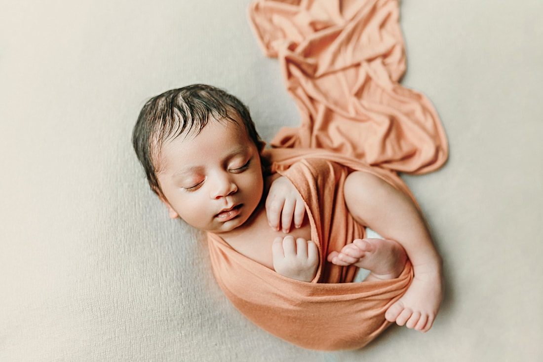newborn baby boy wrapped in orange blanket for newborn portraits in memphis, TN