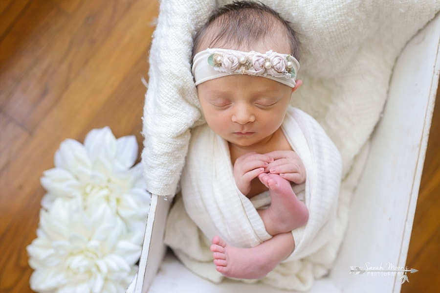 Newborn Photography | Newborn photo of baby girl posed in a white wooden box with white flowers at her Newborn Photo Session in Memphis, TN