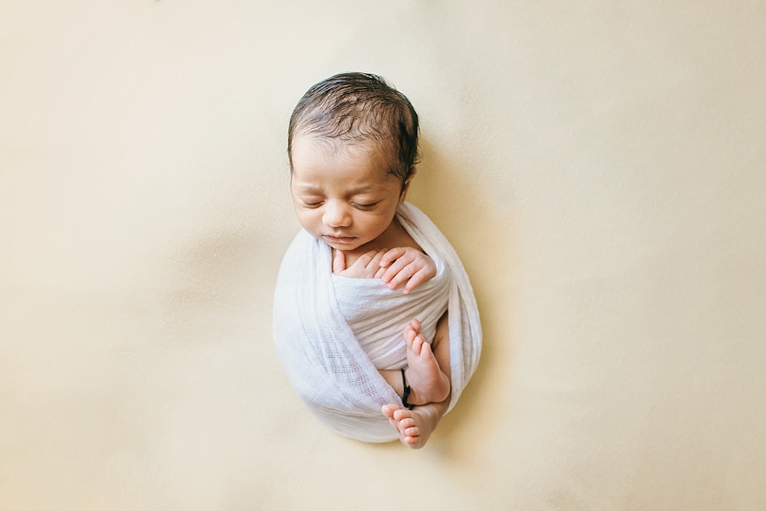 newborn baby wrapped in white on yellow background for newborn photos in memphis