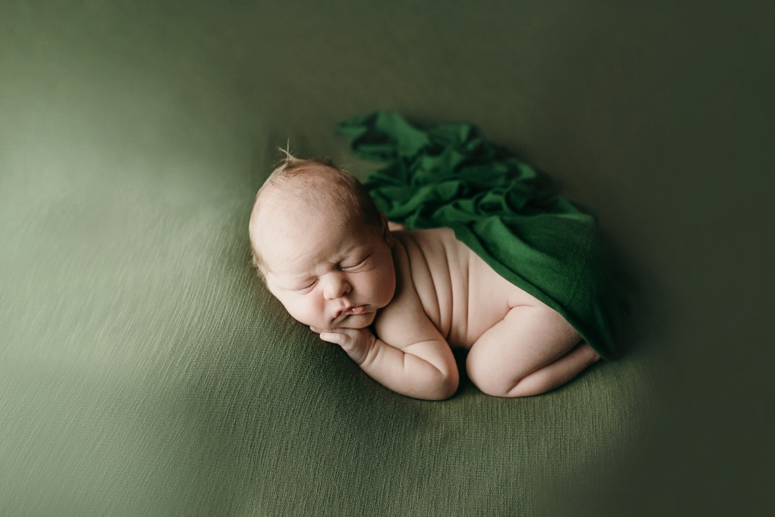 newborn baby boy posed and sleeping on green blanket in Memphis, TN