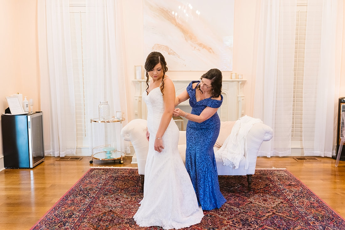 mother of the bride buttoning bride's wedding dress in the bridal suite at Orion Hill in Arlington, TN