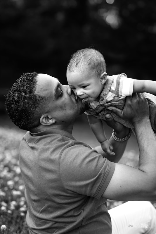 Daddy kissing baby's cheek in a field of clover at Shelby Farms Park