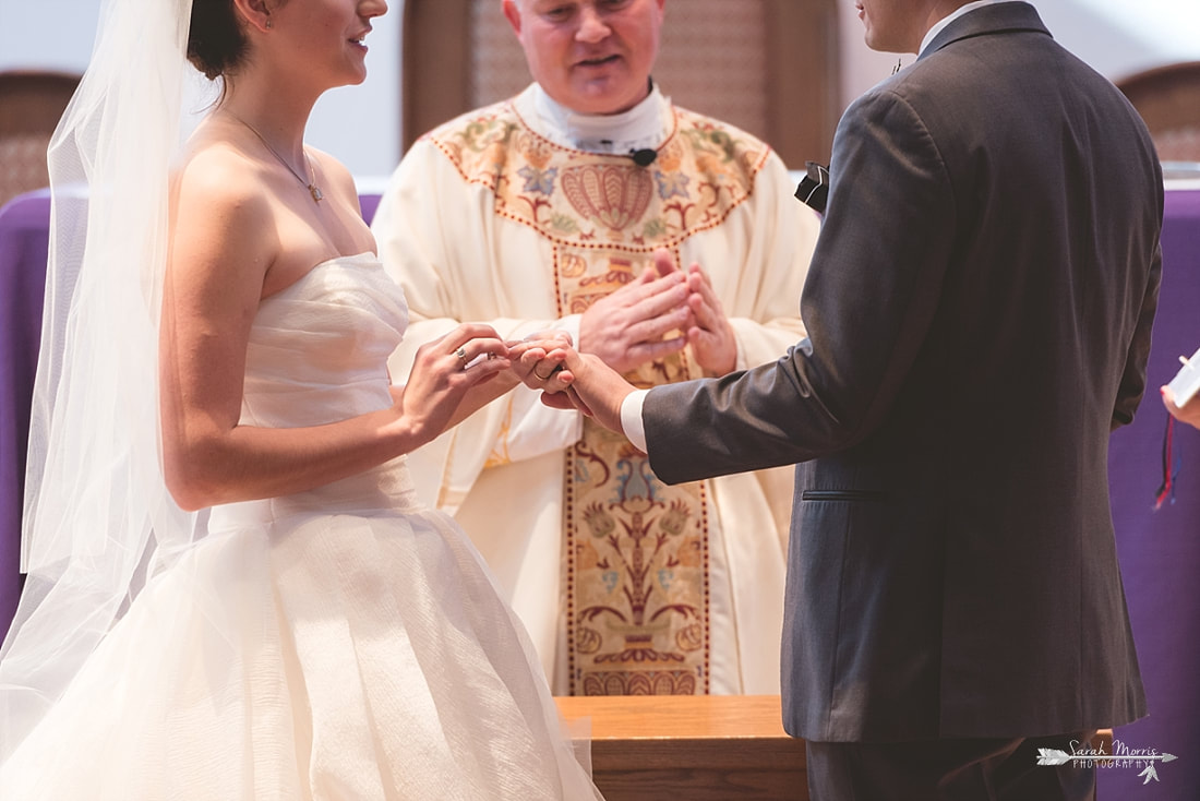 close up of bride putting on the groom's wedding ring at St. Francis of Assisi Catholic Church